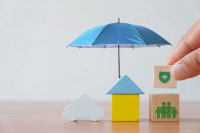 Insurance and investment concept of health, life, accident and travel. Hand picked wooden block with insurance sign and symbol of house, family, car